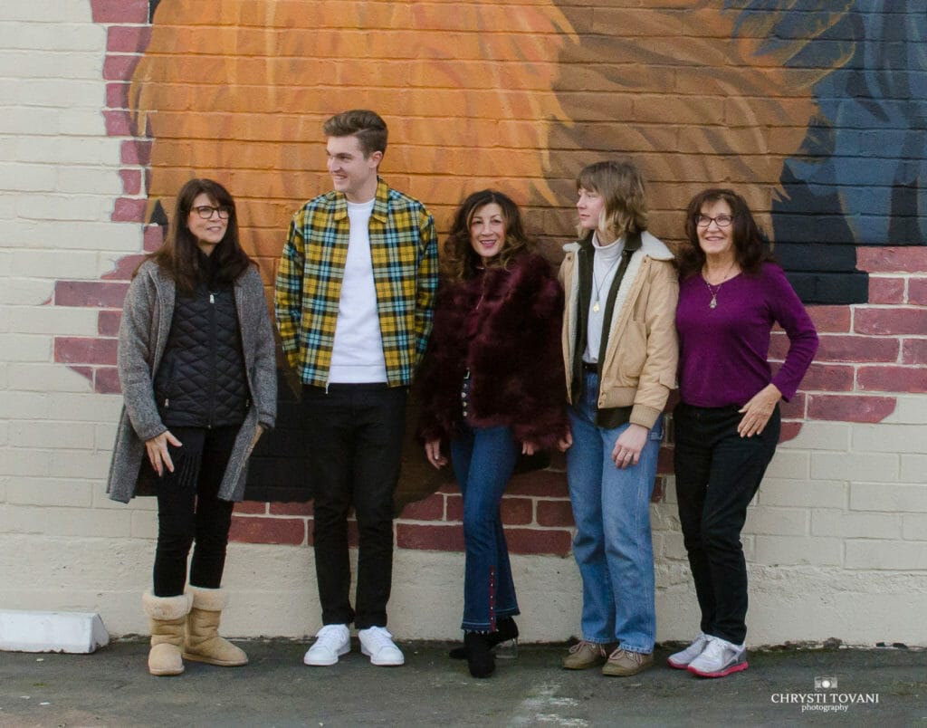 the mural artists standing in front of the mural of hermie the rooster mural in fair oaks village