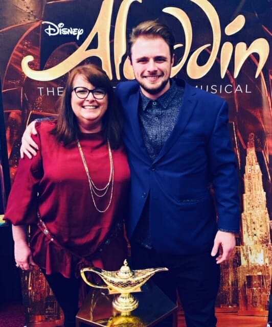 two people standing in front of the Aladdin backdrop at the Sacramento Community Center Theater