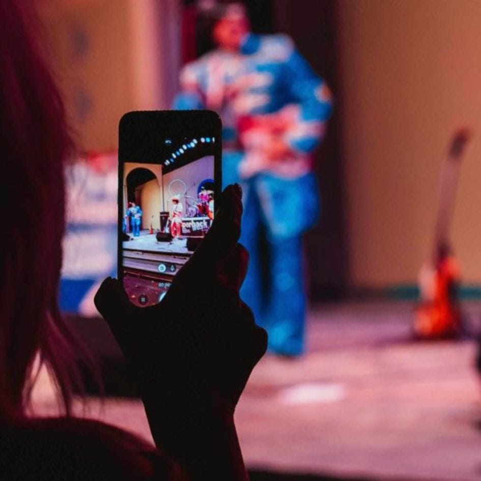 person recording concert with their cell phone