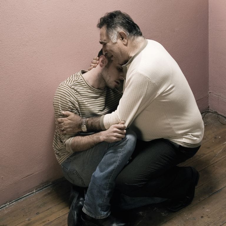 man embracing his addicted son