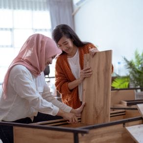 two women putting together a cabinet