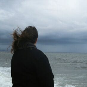 woman looking a ocean on a cold gray day