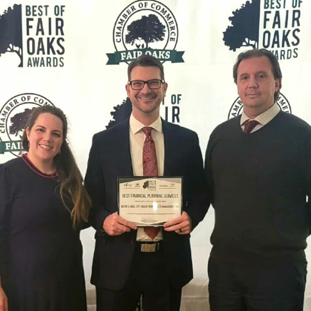 woman and two men holding an award. 