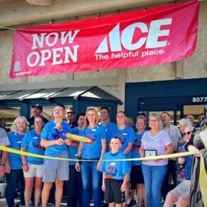 new owners in front of ace hardware about to cut ribbon
